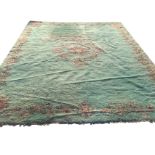 A large wool carpet woven with russet central floral medallion and borders on green thick pile