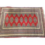A silk woven Kazakh type rug with seven diamond shaped medallions on red field framed by multiple