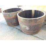 A pair of oak garden barrel planters, the tubs with staves each bound by three riveted metal strap