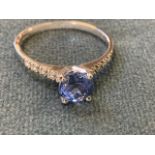 A 14ct white gold sapphire and diamond ring, the round cut, claw mounted Ceylon sapphire of over