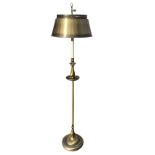 A contemporary brushed-finish brass standard lamp with metal shade on column above a circular