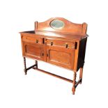 An Edwardian oak sideboard having arched upstand with oval bevelled mirror above a rectangular