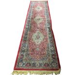 An oriental style runner, the rectangular red floral field woven with three oval scalloped