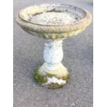 A composition stone birdbath with circular bowl on leaf cast column raised on mound plinth. (15.