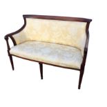 A Victorian style mahogany canapé with rounded upholstered back and scrolled arms on turned spindles
