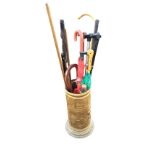 An embossed brass tubular stick stand on moulded foot containing four hickory shafted golf clubs,