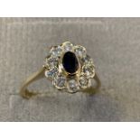 An 18ct gold fine sapphire cluster ring, the oval bezel set sapphire of under half a carat, framed