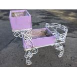 A painted wrought iron pram shaped garden planter with boxes on platforms with scrolled