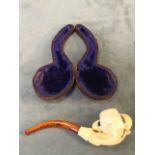 A leather cased carved meerschaum pipe with amber coloured mouthpiece, and body in the form of a