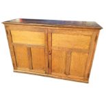 A late Victorian oak cupboard with rectangular moulded top above two panelled doors, raised on