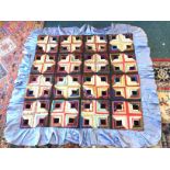 A multicoloured square patchwork quilt sewn in panels of pleated squares around black velvet