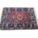 A Baluchi style Turkestan rug woven with three crosses to central red field having serrated