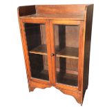 An Edwardian glazed oak cabinet with enclosed top shelf by channelled moulded frame around two