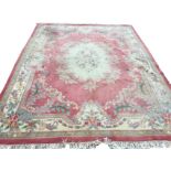 A Chinese thick pile carpet woven with oval central floral medallion on pink field with scrolled