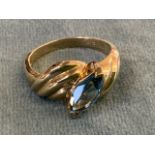 A 14ct yellow gold blue topaz ring, the elipse shaped stone flanked by waved gold shoulders.