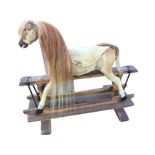 An antique rocking horse, the skin covered animal with carved nose and glass eyes, mounted on