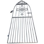 A tall gothic shaped wrought iron garden gate with tubular spindles and scrolled decoration,