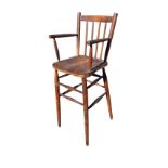 An elm high chair with spindleback above a solid seat, raised on turned legs & stretchers.