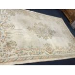 A pale Wilton style carpet woven with central foliate scrolled medallion on ivory field, framed by