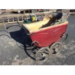 A vintage pram with tin body having padded lining and concertina hood, supported on a sprung frame