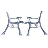 A pair of cast iron bench ends with scrolled decoration to channelled frames, the seat and back