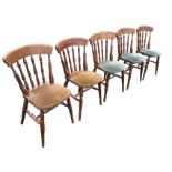 A set of five stained spindle-back dining chairs, with shaped upholstered seats raised on turned