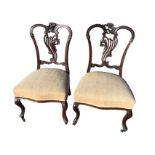 A pair of late Victorian mahogany salon chairs with pierced scroll carved backs above upholstered