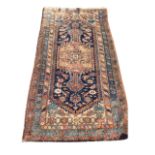 A Bokhara rug woven with rectangular panel on blue floral field framed by serrated border, the