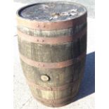 An oak whiskey barrel, the staves bound by six riveted metal strap bands. (35in)