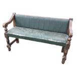 An upholstered settle, the padded back in moulded frame with shaped carved arms on turned columns,