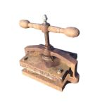 A Victorian cast iron press with brass acorn finial above handle with screw below, having