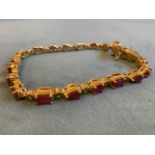An African ruby bracelet, the 19 gems with various cuts in gold coloured claw settings, hinged and