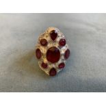 An African ruby and silver ring, the graduated stones bezel set in a shield with scalloped edge