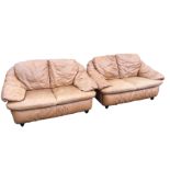 A pair of two-seater leather sofas with integral back, seat and armrest cushions, raised on