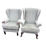 An upholstered wing armchair with sprung back & seat having loose cushion, with shaped arms raised