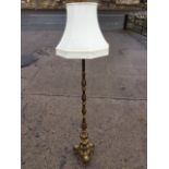 A brass standard lamp with leaf cast fluted column on bulbous base with three scrolled supports,