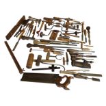 A collection of wood handled steel tools including chisels, screwdrivers, braces, a mitre saw, a