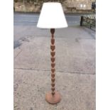 An eastern carved standard lamp, the bobbin turned column chisel carved with leaf foliage, with
