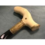 An ivory handled gold mounted ebony cane, the shaped pistol grip handle with cross-hatched panels