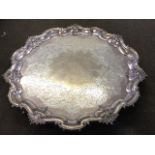 A large hallmarked circular scalloped silver salver with foliate scrolled engraved decoration and