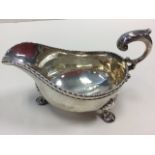 A George III hallmarked silver sauceboat with gadrooned rim and scrolled handle, raised on shell paw