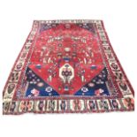 An Iranian wool carpet, the hexagonal central panel with birds and flowers on red ground, with