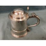 A Queen Anne silver tankard with domed hinged cover having scrolled thumbpiece, raised on circular