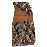 A carved block hand printing panel with leaves and flowers, the label to verso detailing the