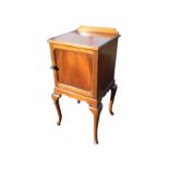 An Edwardian mahogany pot cupboard, the moulded top with upstand above a panelled door, raised on