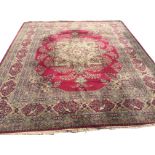 An Axminster style carpet woven with central paisley style medallion on maroon ground with