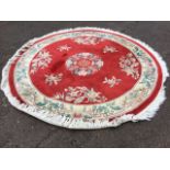 A circular Chinese thick pile wool rug woven with vases of flowers on red field, the frieze of