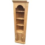 A reproduction pine corner cupboard with moulded cornice above an arched apron and three shaped