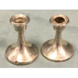 A pair of hallmarked silver candlesticks with urn shaped candleholders on flared circular bases -