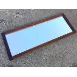 A contemporary rectangular mirror, the mahogany frame enclosing a bevelled plate. (62.25in x 24in)